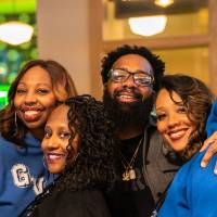 Four event guests standing close together and smiling for photo
